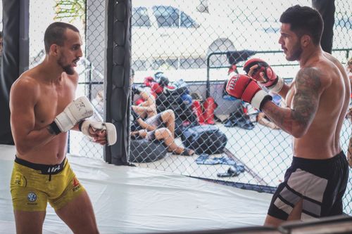 Free Two male fighters sparring in a gym cage, demonstrating martial arts training. Stock Photo