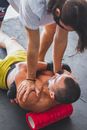 Trainer Helping Athlete with Stretching on Foam Roller