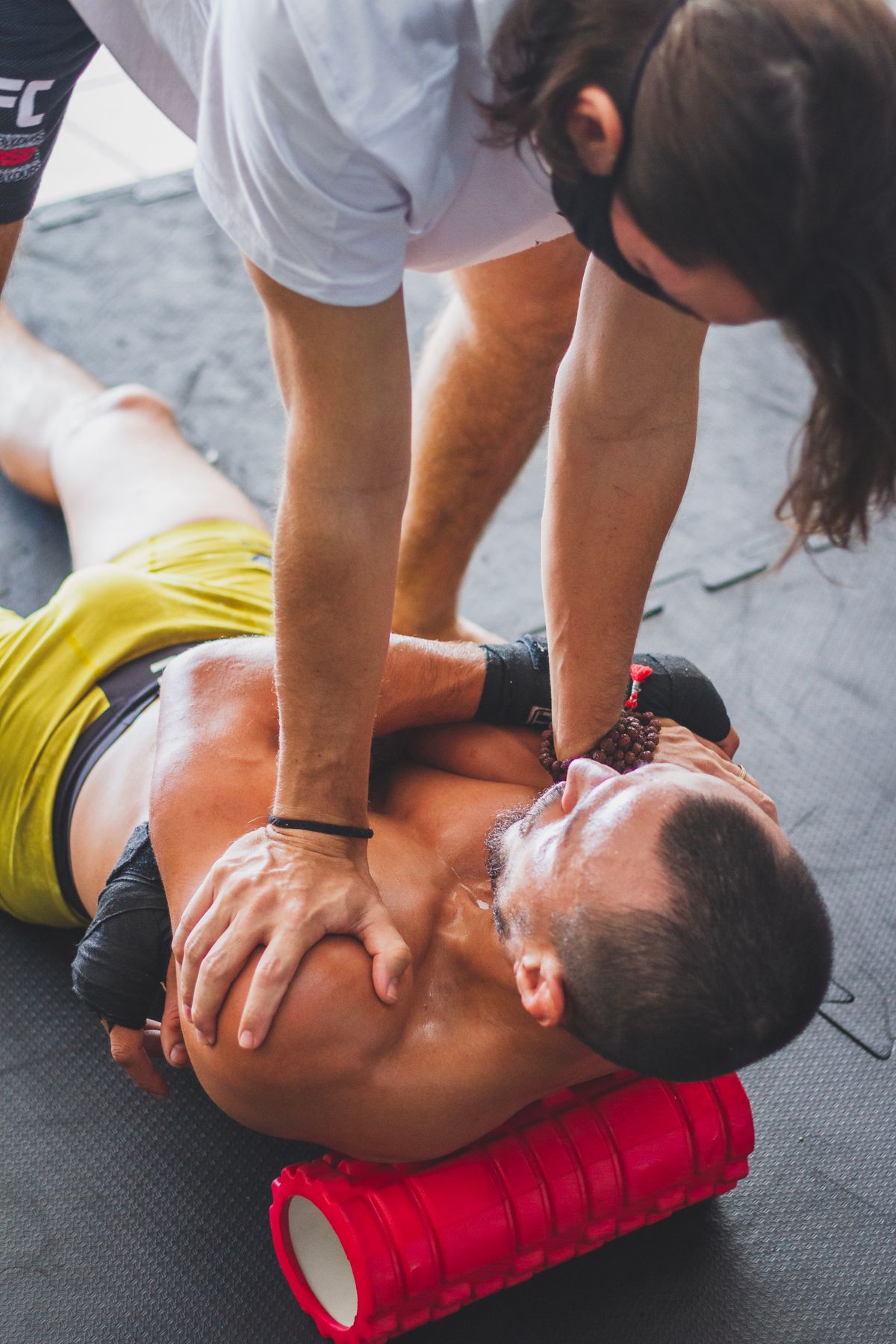 Trainer helping an athlete with foam roller recovery and stretching