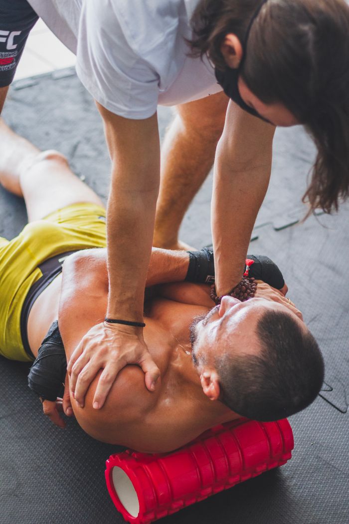 Deportista realizando estiramientos con ayuda de un entrenador