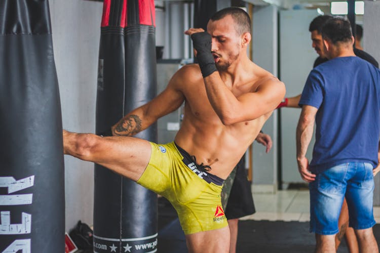 Man Kicking A Punching Bag On A Training 