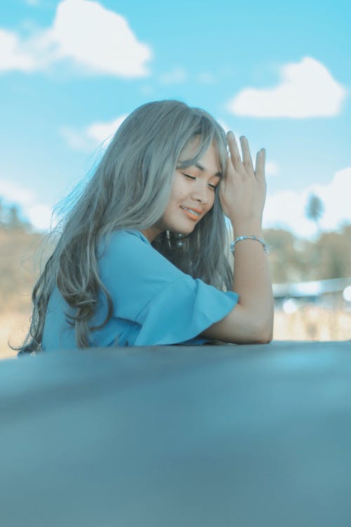 Free Happy model with closed eyes smiling while touching hair by hand with bracelet Stock Photo