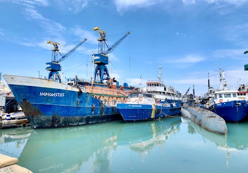 Vibrant harbor showcasing large ships and cranes under a clear blue sky.