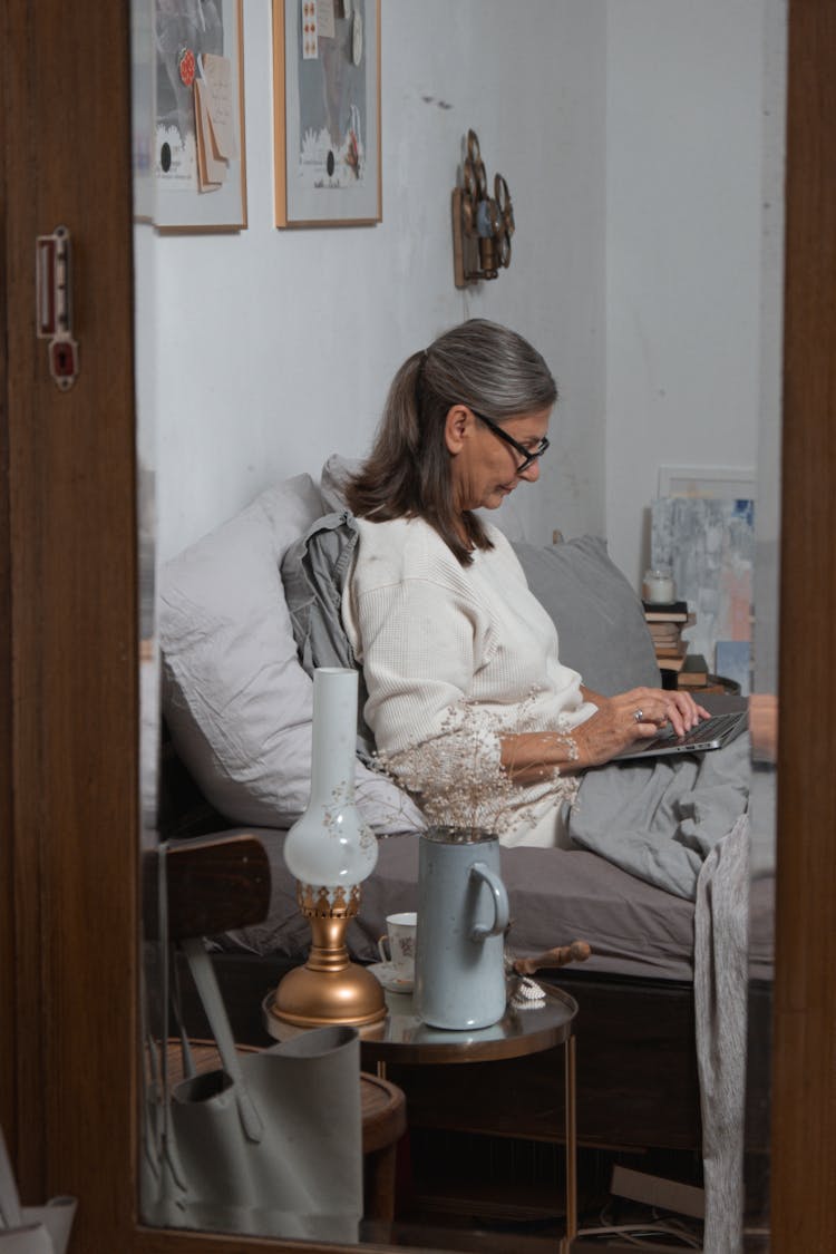 Woman Sitting In Her Bed And Using A Laptop 