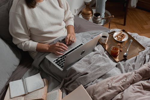 Person in White Long Sleeve Shirt Using Silver Laptop