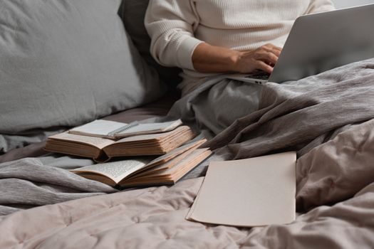 A cozy setup with an open laptop and books on a bed, perfect for relaxing work or study sessions.
