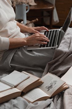 A person working from home on a laptop surrounded by books, fostering a cozy and productive atmosphere.