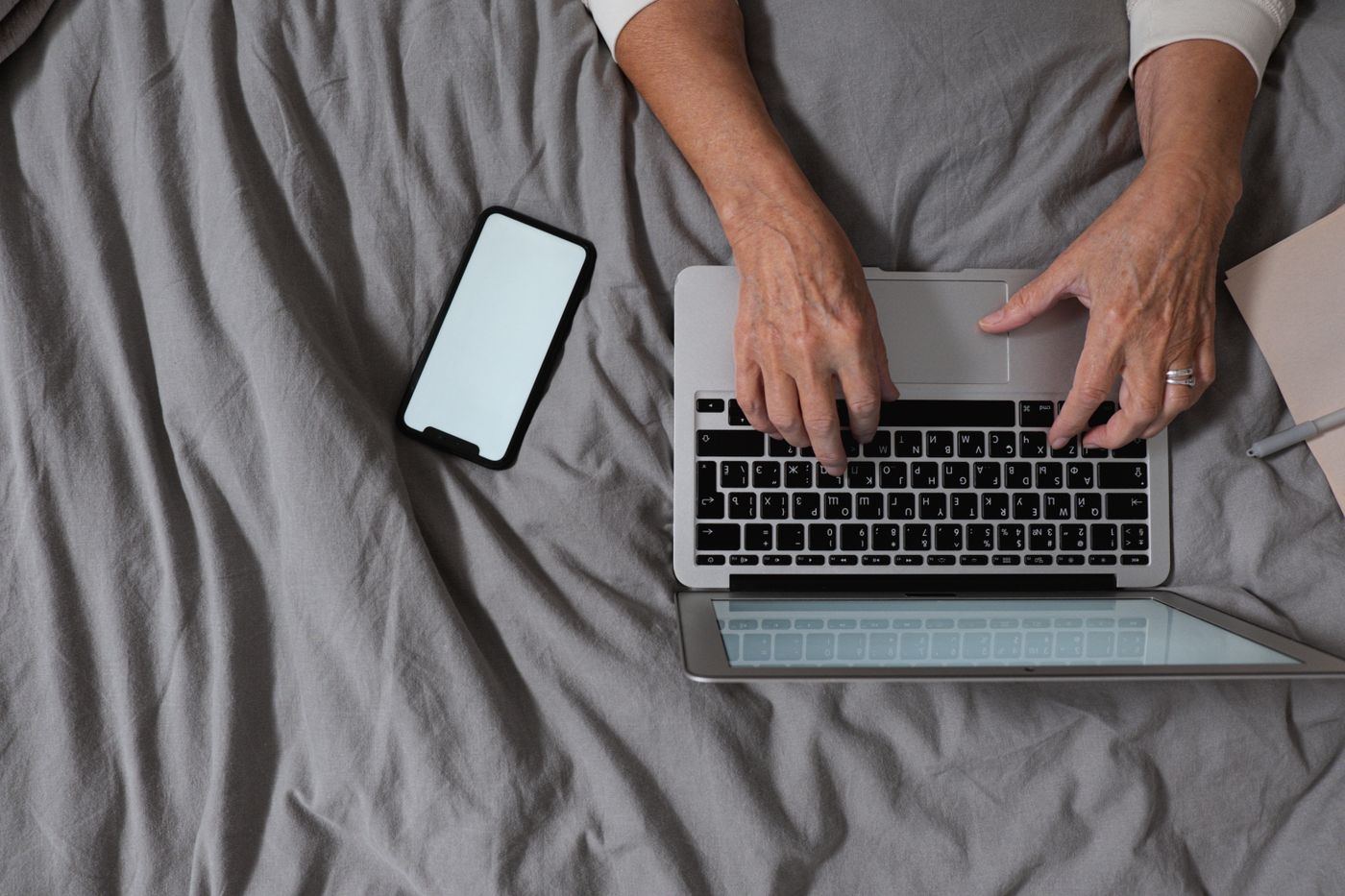 Pessoa digitando em notebook com smartphone ao lado, representando automação digital, segurança, produtividade e tecnologia no trabalho