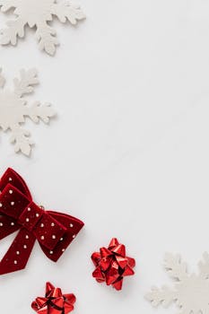 Red bows and white snowflakes on a white background, perfect for holiday themes.