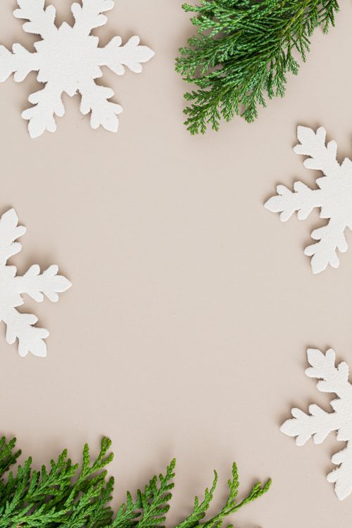 Free Christmas-themed background with snowflakes and green branches creating a festive frame. Stock Photo