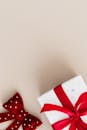 这是一幅极简主义图像，米色背景上有一个系着红丝带和蝴蝶结的礼品盒，非常适合节日庆祝