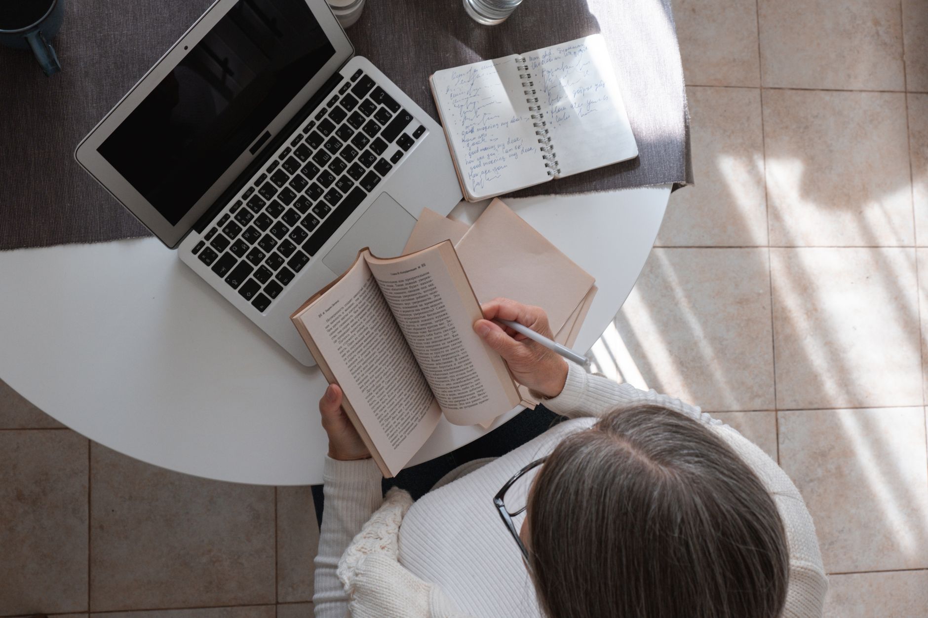 A coach writing at a laptop beside an open notebook and a coffee, drafting the week's email