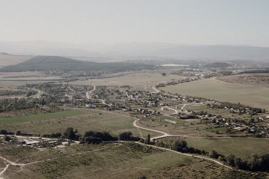 Aerial view of a rural community with farmlands and roads under a clear sky.