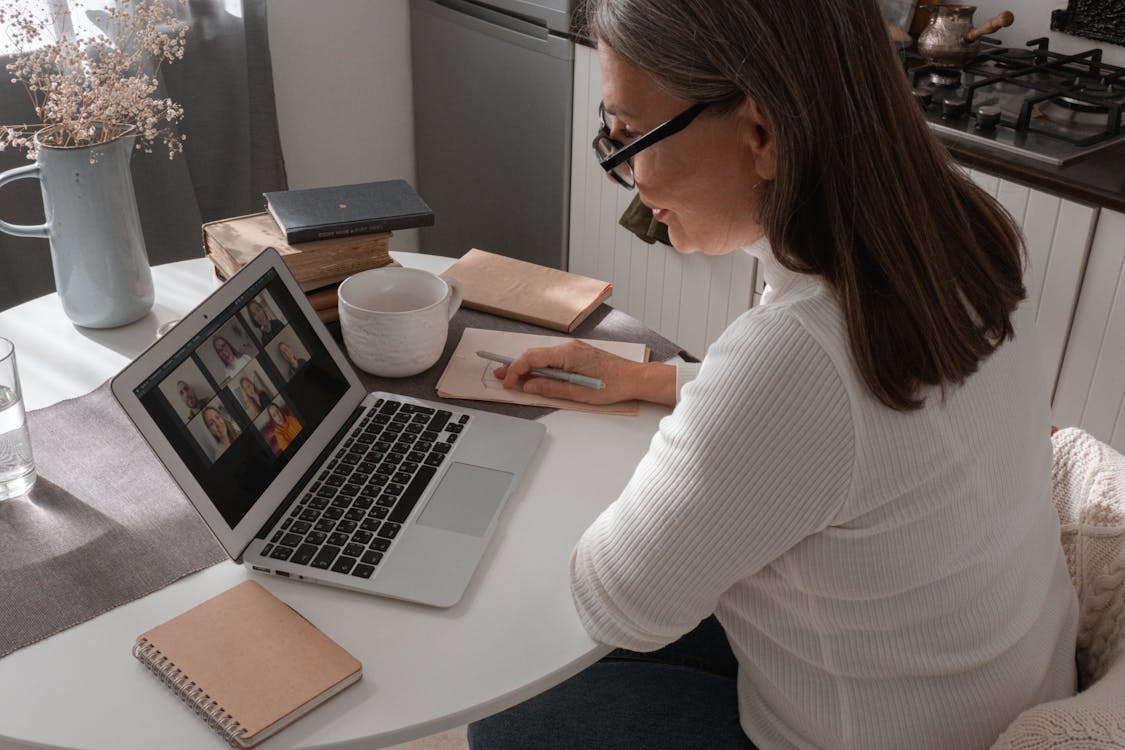 Free Woman in White Sweater Using Macbook Air Stock Photo