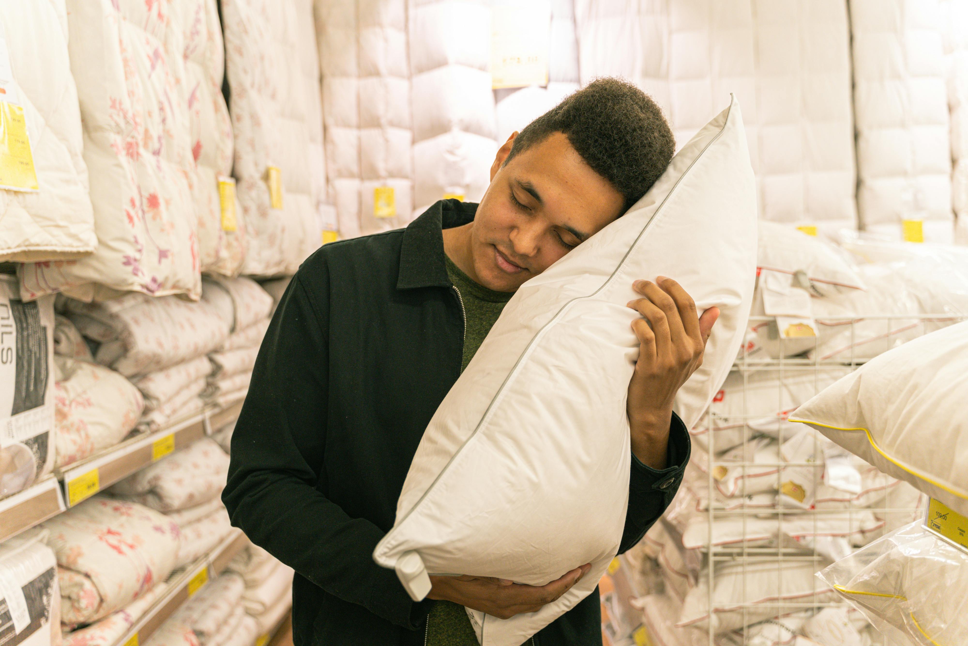 man in black long sleeve shirt holding white pillow