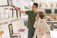 一对夫妇在家具店光线充足的过道里检查椅子