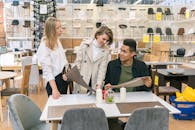 三个年轻人在一家时尚的家具店里讨论餐桌选择，象征着团队合作和现代室内设计