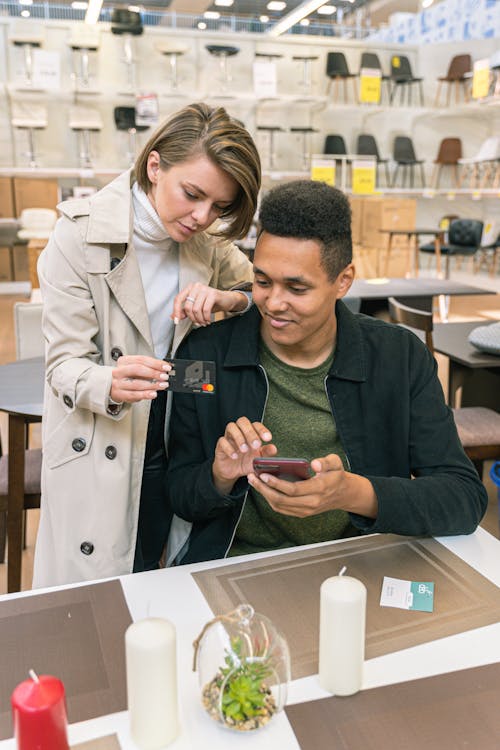 Free Man and Woman in Furniture Shop Paying Via Credit Card Stock Photo