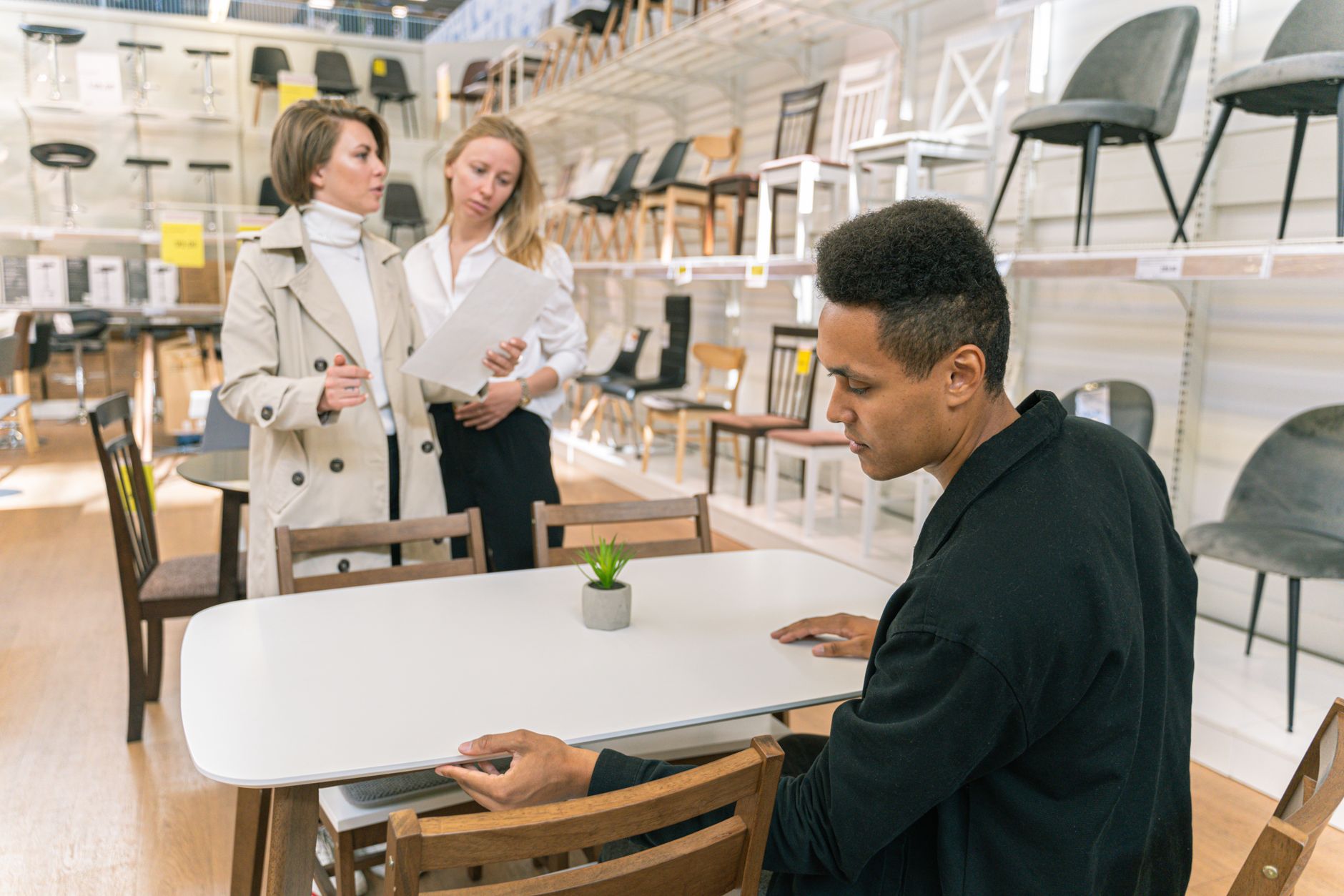 A professional discussion takes place in a well-lit furniture store showroom with diverse employees.