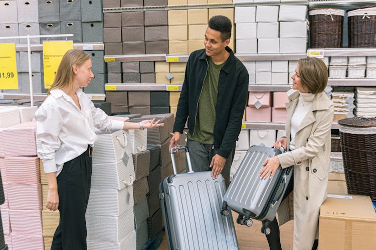 Man And Woman In Furniture Shop Choosing Suitcase