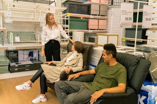 在一家现代家居用品商店，购物者在销售人员的指导下试用皮椅