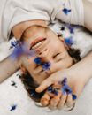 一名男子闭着眼睛，摆出宁静的姿势，躺在蓝色矢车菊中