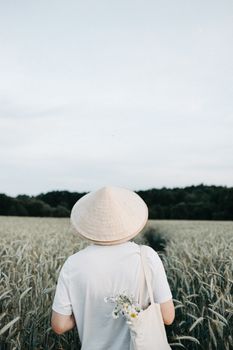 白天，一个人戴着传统亚洲帽子，站在郁郁葱葱的麦田里
