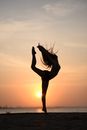 Woman Midair in an Acrobatic Pose on a Beach at Sunset 