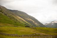 Green Grass Field Near Mountain Under White Sky
