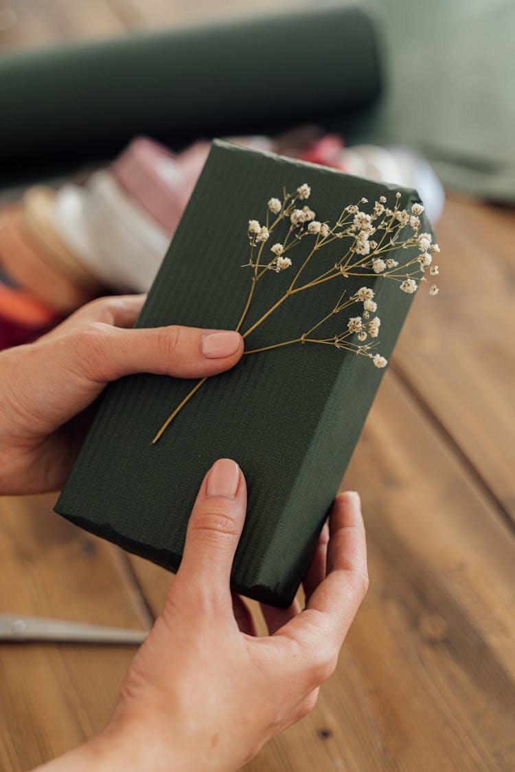 A Person Holding A Gift And White Flowers