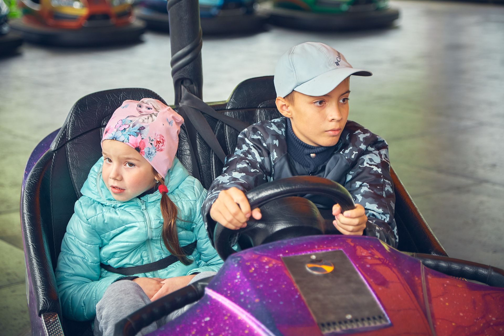 Two kids having fun driving a bumper car ride at an amusement park. Exciting and playful moment captured.