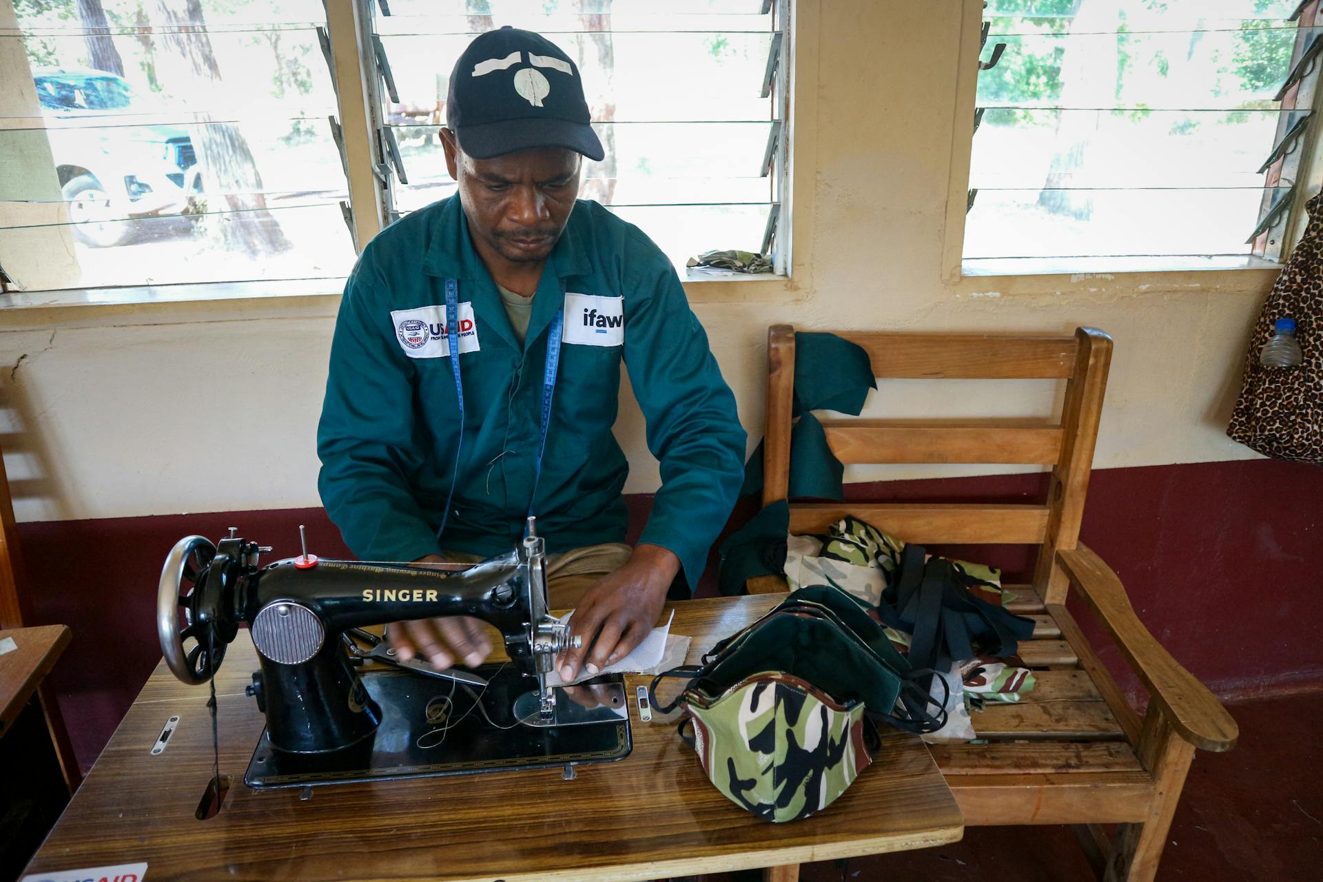 African man sewing face masks at a workshop in Malawi for a nonprofit initiative.