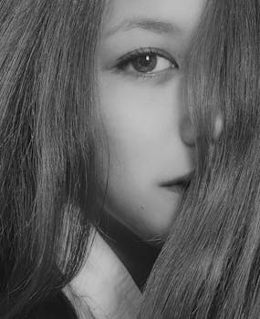 Striking black and white portrait of a woman partially obscured by hair, showcasing her eye.