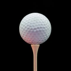 White golf ball on a tee against a black background