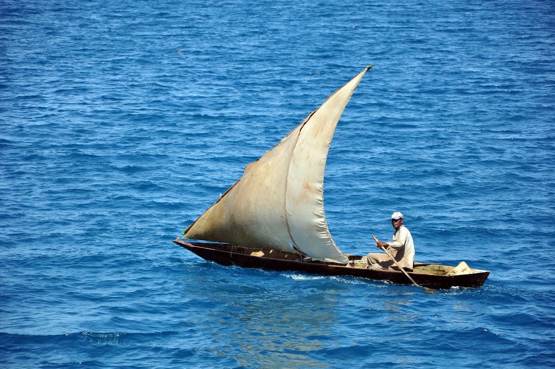 Man and Woman Sitting on Brown Boat on Blue Sea