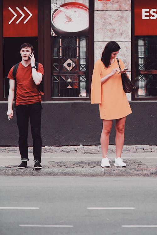 Two People Using their Phones in a City