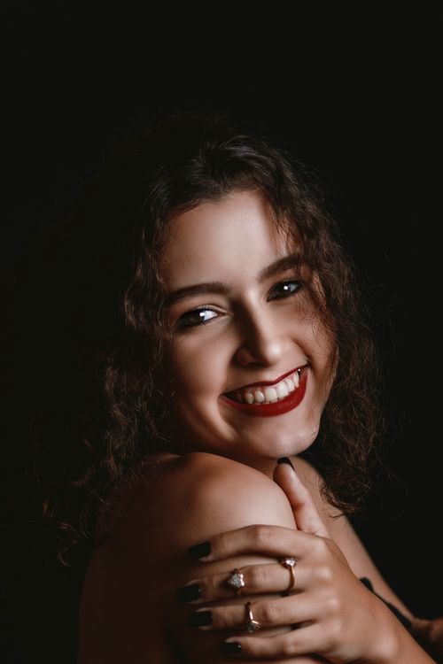 Free Portrait of a smiling woman with red lipstick against a dark background. Stock Photo