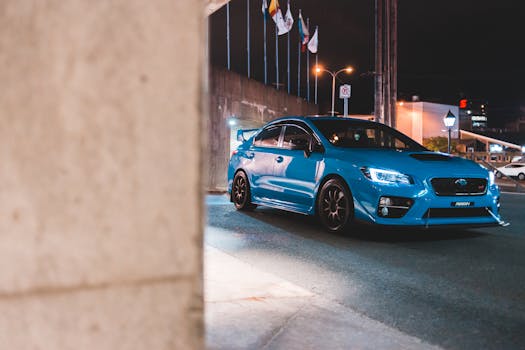 Contemporary luxury blue automobile with shiny headlights on asphalt roadway near government building in twilight