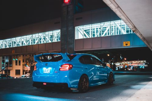 Free Rear bumper of contemporary luxury blue auto on asphalt roadway near city building at night Stock Photo