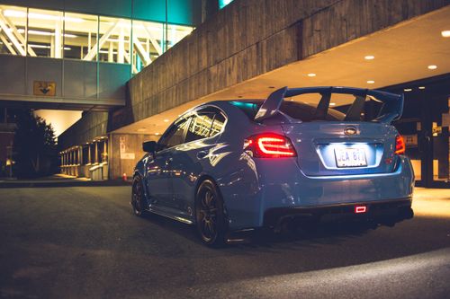 Free Modern luxury auto with shiny taillights on asphalt roadway near urban building in town at dusk Stock Photo
