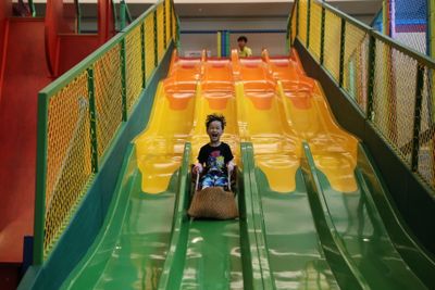 A cheerful child sliding down a colorful slide in an indoor playground