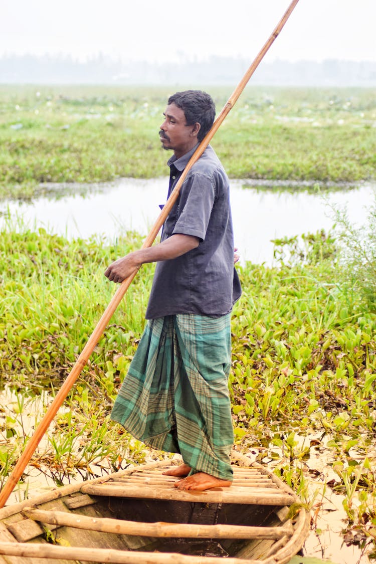 Man Holding A Stick While Standing On A Boat