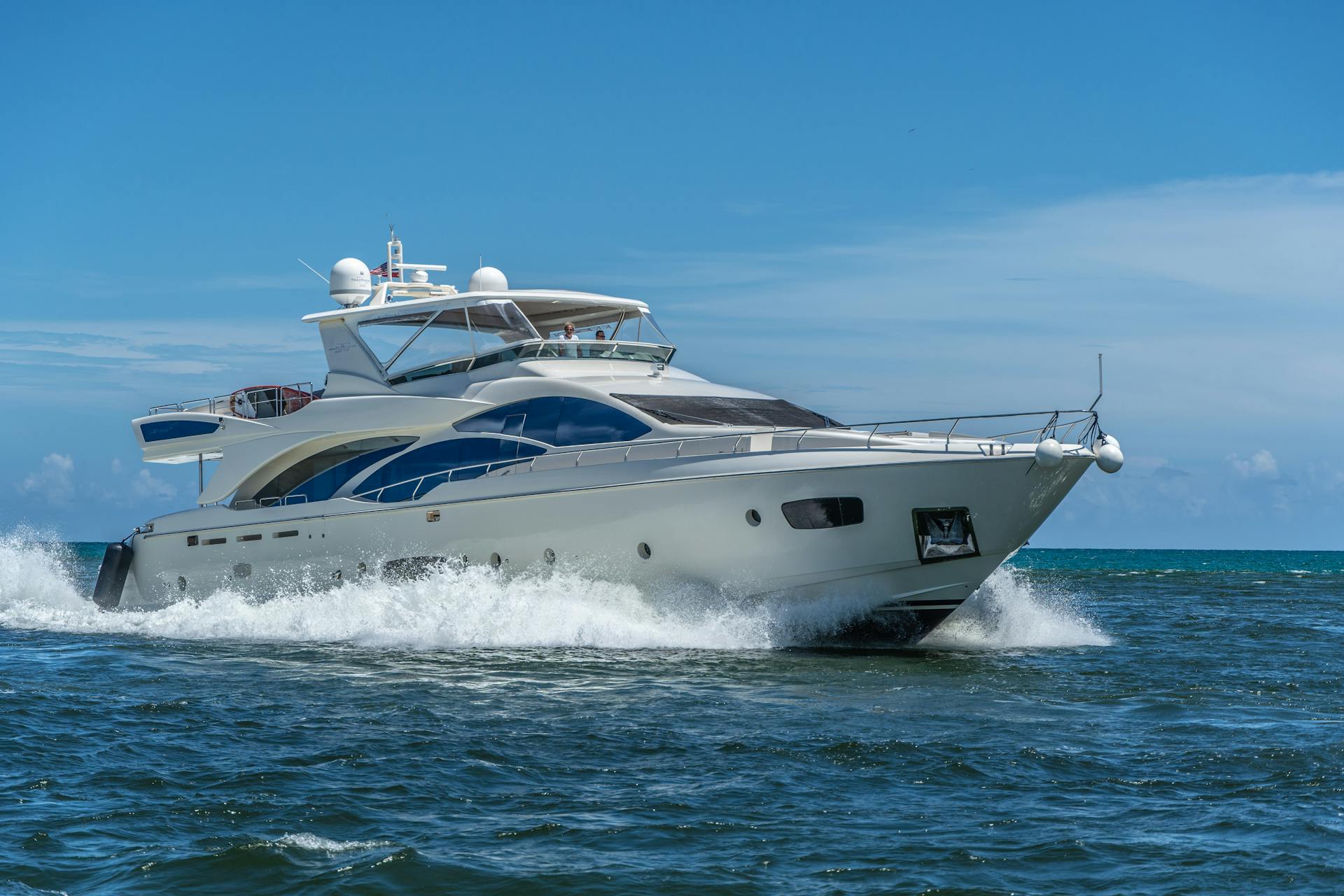 A sleek luxury yacht cruising through the ocean under a clear blue sky near Miami, Florida.