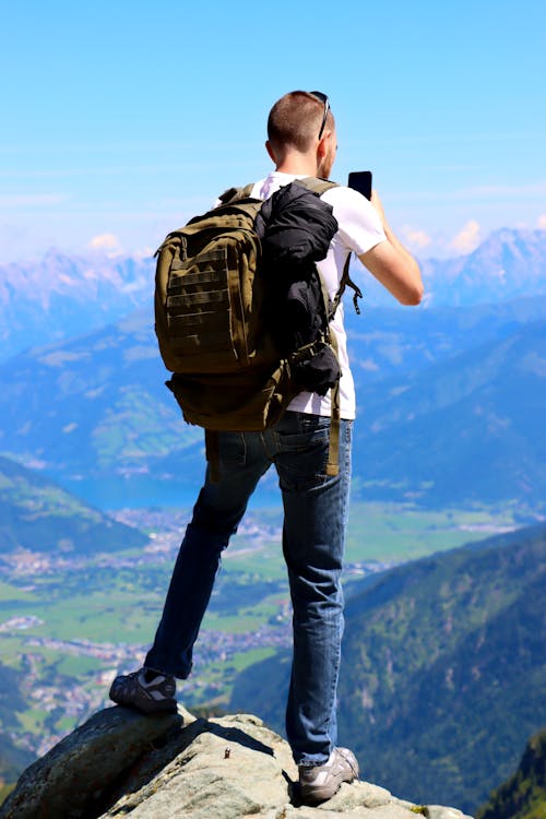 Man Standing on Mountain Peak Taking Pictures