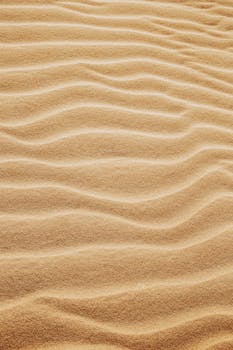 From above of fine wavy yellow sand spreading on smooth surface in hot sunny summer day