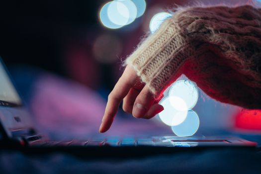 Cozy atmosphere with a hand typing on a laptop surrounded by bokeh lights.