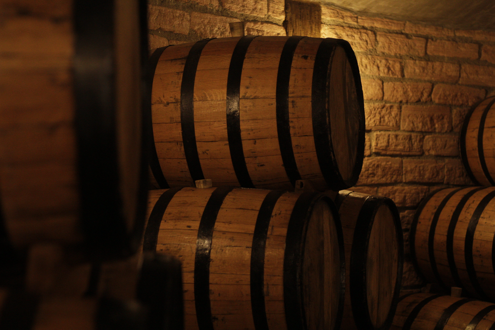 Casks heaped together in an underground cellar under warm light — photo by Jonathan Nenemann on Pexels