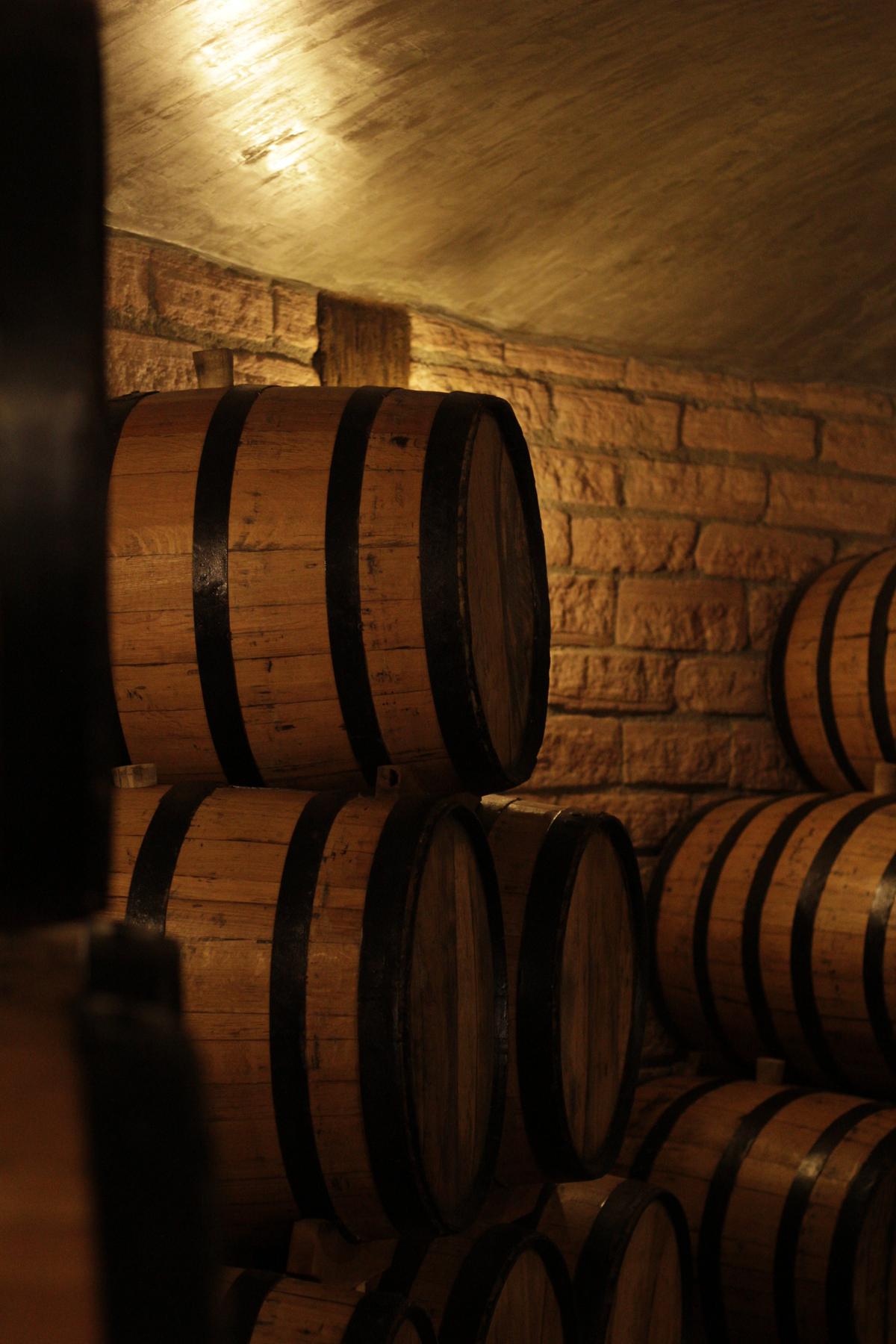 Pile of oak barrels with aging wine stacked together in traditional cellar of winery