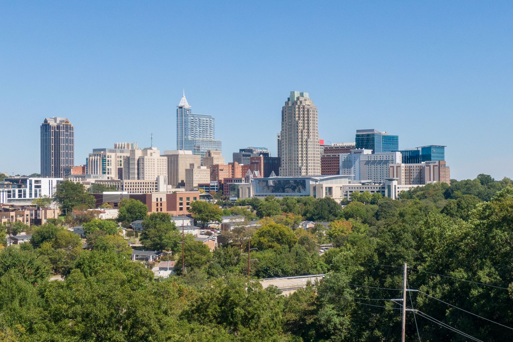 A clear view of Raleigh's skyline, showcasing modern skyscrapers and urban greenery.