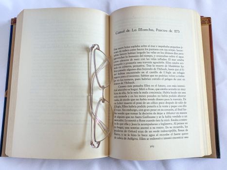 An open book with eyeglasses on a white surface, suggesting reading and relaxation.
